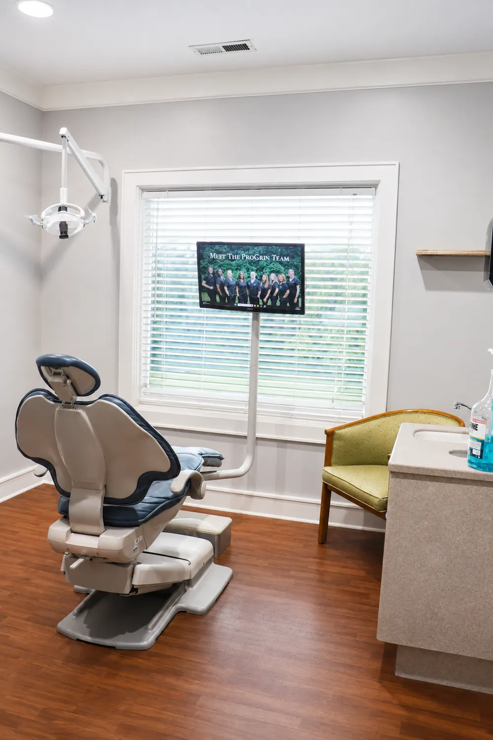 Modern dental treatment room with an overhead exam light and a mounted patient television